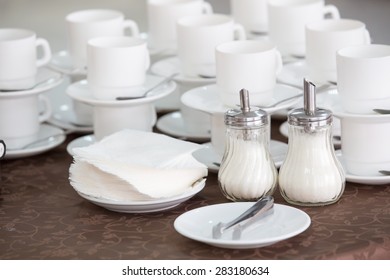 clean white cups and saucers, two sugar bowls and napkins