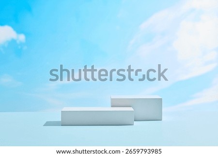 Clean white display blocks with clear blue sky background, creating an open space for outdoor cosmetics or sunscreen product photography.