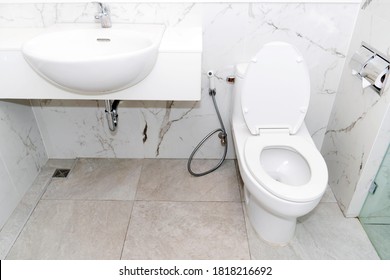 Clean, white toilet and sinks and paper rolls with mable wall