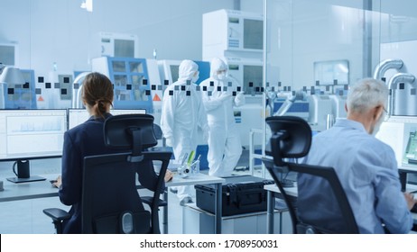In Clean Workshop: Professional Workers in Coveralls and Masks Use Laptop and Talk. Inside Factory Office: Female Electronics Engineer Works on Computer, Screen Shows Printed Circuit Board 3D Design - Shutterstock ID 1708950031