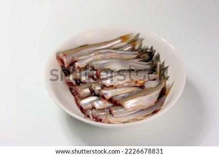 Cleaned small headless fish in a white plate