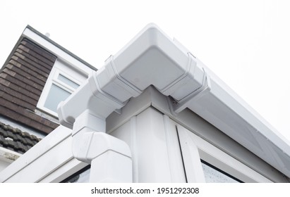 Cleaned white plastic pvc gutters and drain pipes that were blocked and full of green mould on the plastic fascias.  Blocked drains and guttering need window cleaners and regular maintenance - Shutterstock ID 1951292308
