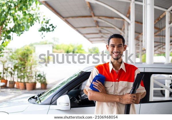 Cleaner car service adult with uniform for clean vehicle\
to customer.Smart worker car care prepare equipment for vacuum\
dust. 