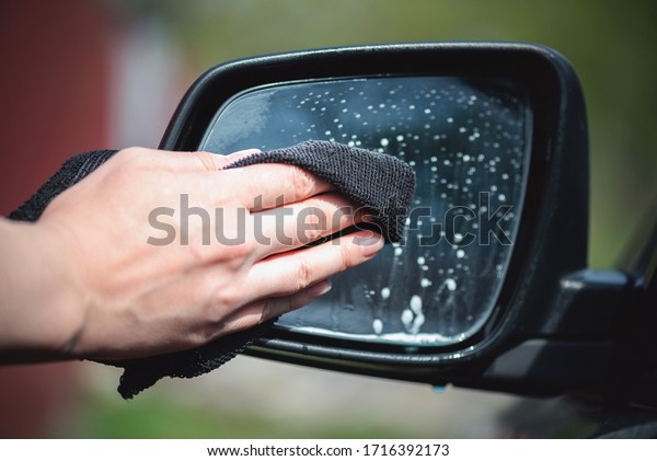 Cleaner is\
cleaning a car exterior mirror close\
up.