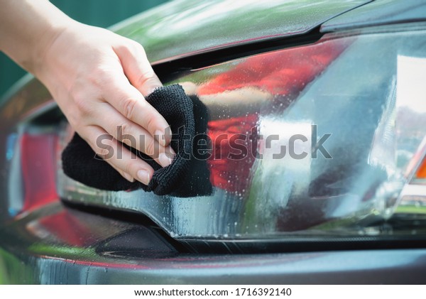 Cleaner\
is cleaning a car headlights with a rag close\
up.