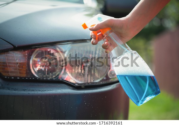 Cleaner\
is cleaning a car headlights with a rag close\
up.