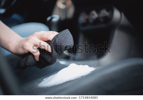 Cleaner is cleaning a car seats with foam cleaner\
close up.