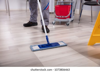 Cleaner Cleaning Hardwood Floor With Mop At Workplace