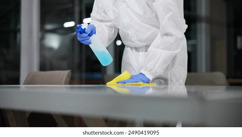 Cleaner, cleaning table and person in office for fumigation, spray disinfect and safety suit from disease risk in building. Maintenance, chemical liquid and pest control of health, hygiene and virus - Powered by Shutterstock