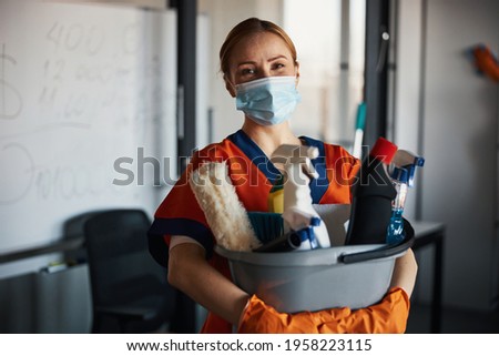 Cleaner in a face mask showing her cleaning products Foto d'archivio © 