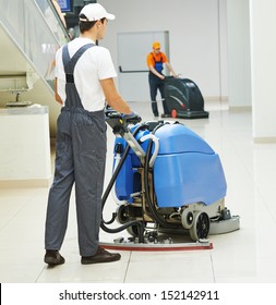 Cleaner male man workers with mop in uniform cleaning corridor pass or hall floor of business building