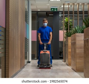 Cleaner With The Mask On His Face Cleans The Hard Floor In The Office With Walk Behind Scrubber Dryer Machine.Cleaning And Maintenance Concept