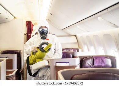 Cleaner officers hold cleaning device on airplane passenger cabin. An employee sprays disinfectant aboard a plane, during airline's sanitary measures to help curb the spread of Coronavirus pandemic.