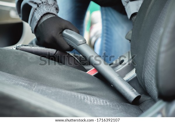 Cleaner vacuuming car\
interior close up.