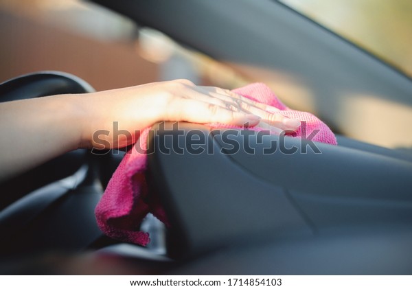 The cleaner wipes and polishes the car dashboard with\
a rag close up.