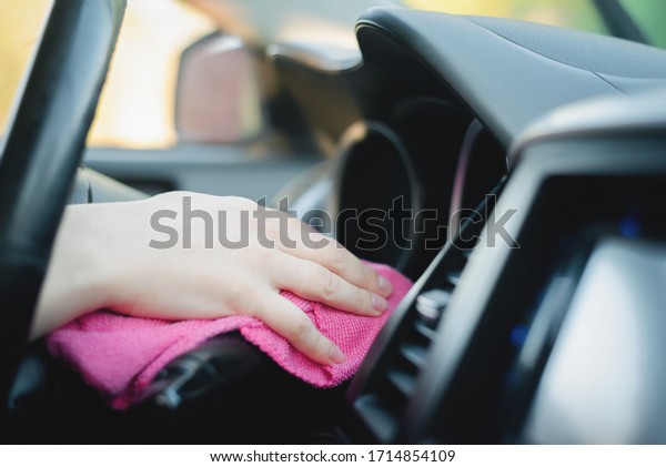 The cleaner wipes and polishes the car dashboard with
a rag close up.
