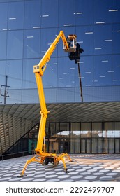 Cleaner worker using a cherry picker to clean a glas facade of a contemporary office building