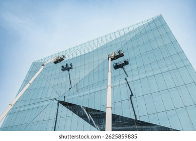 Cleaner worker using a cherry picker to clean a glas facade of a contemporary office building.
