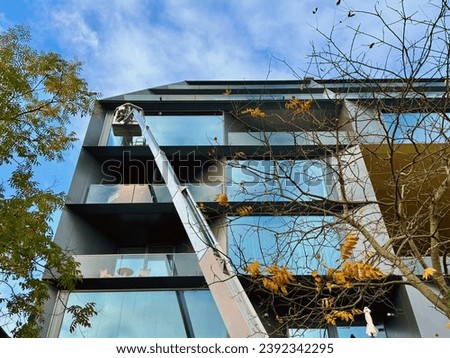 Cleaner worker using a cherry picker to clean a glas facade of a modern building