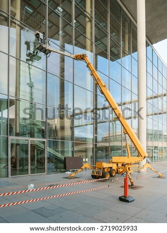 Cleaner worker using a cherry picker to clean the glas facade of a contemporary building