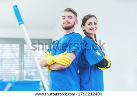 Cleaners being proud of their service standing arms folded, team of woman and man