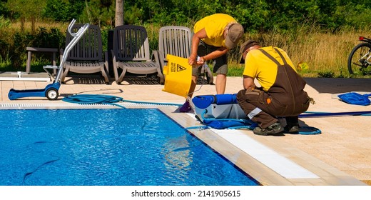 The Cleaners Are Engaged In Cleaning The Pool With Automatic Cleaning Robot. Bucket With The Inscription Caution Wet Floor Concept Photo  Pool Cleaning, Hotel Staff, Service.