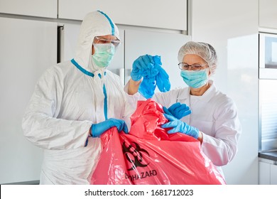 Cleaners With Protective Clothing In Clinic Remove Disposable Gloves During A Covid-19 Epidemic