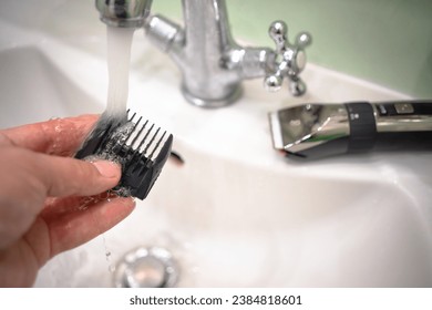 Cleaning the attachments for the hair clipper. Wash the electric clipper under the tap.