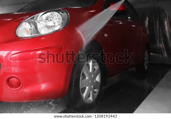Cleaning auto with high pressure water jet at car\
wash, closeup