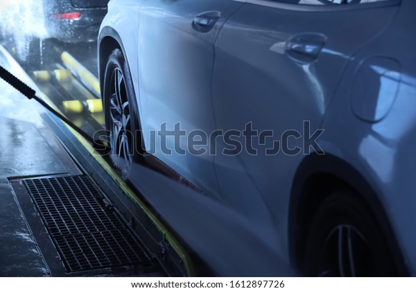 Cleaning\
auto with high pressure water jet at car\
wash