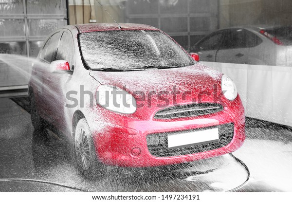 Cleaning automobile with high pressure water jet at\
car wash