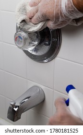 Cleaning Bath Tub Faucet Wearing Silicone Gloves And Spraying With A Cleaning Aerosol.