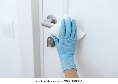 Cleaning black door handle with an antiseptic wet wipe in blue gloves. Woman hand using towel for cleaning. Sanitize surfaces prevention in hospital and public spaces against corona virus. - Shutterstock ID 2088189034
