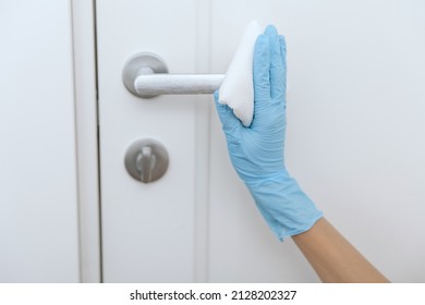 Cleaning black door handle with an antiseptic wet wipe in blue gloves. Woman hand using towel for cleaning. Sanitize surfaces prevention in hospital and public spaces against corona virus. - Shutterstock ID 2128202327