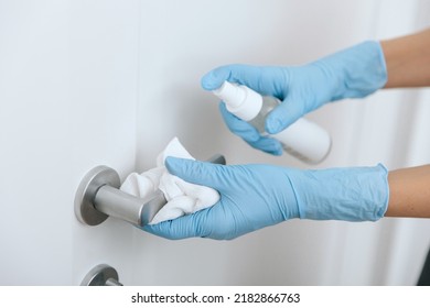 Cleaning Black Door Handle With An Antiseptic Wet Wipe, Blue Gloves And Sanitizer. Sanitize Surfaces Prevention In Hospital And Public Spaces Against Corona Virus. Woman Hand Using Towel For Cleaning.