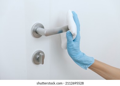 Cleaning black door handles with an antiseptic wet wipe and blue gloves. Sanitize surfaces prevention in hospital and public spaces against corona virus. Woman hand using towel for cleaning. - Shutterstock ID 2112695528