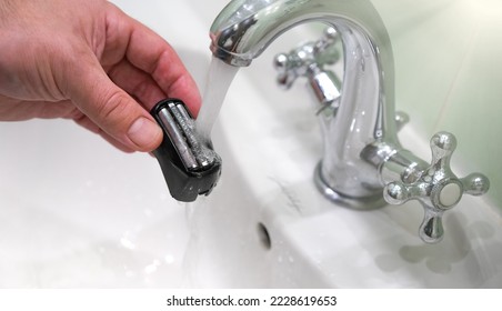 Cleaning the blades from the shaving machine under the tap.Washing the electric razor mesh under water. - Powered by Shutterstock