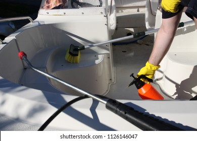 Cleaning boat with high pressure washer, pump spray bottle, and brush, by hands 