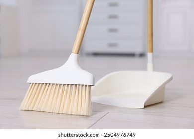 Cleaning broom and dustpan on wooden floor indoors - Powered by Shutterstock