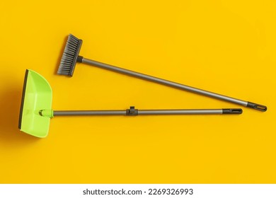 Cleaning broom with dustpan on yellow background - Powered by Shutterstock