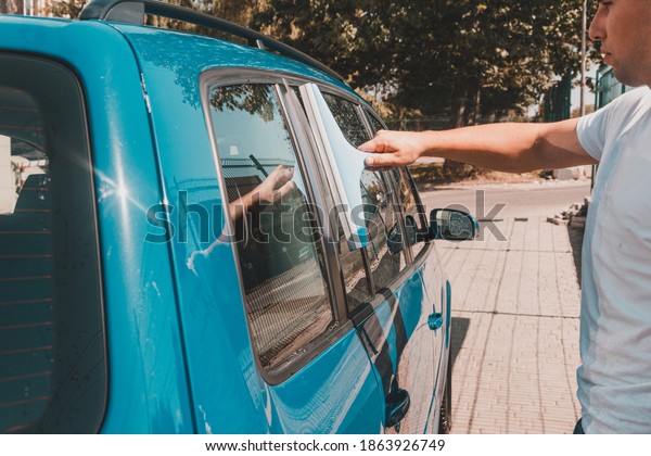 cleaning the car glass, a man wipes excess water\
from the glass in the\
car.