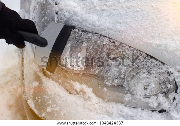 Cleaning the car headlight\
from snow