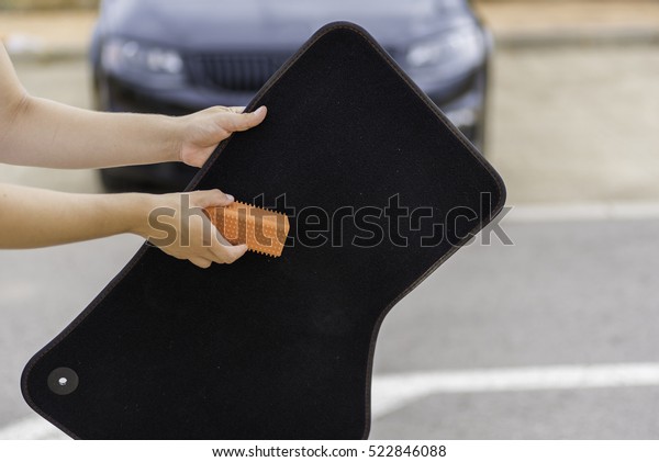 Cleaning car mats with a\
utensil.