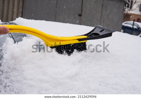 cleaning the car from snow\
with a brush