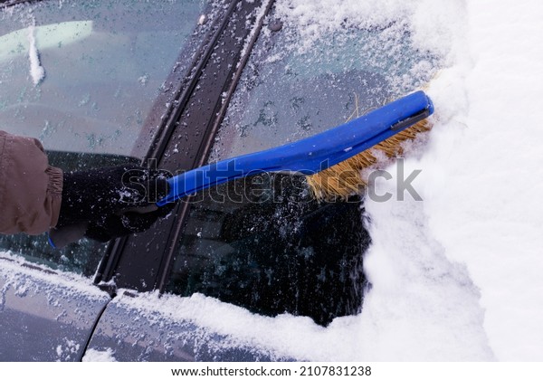 Cleaning the car from snow in\
winter. Snow-covered car after a snowfall. Deteriorating weather\
conditions in winter, Winter Snow Storm and Bad Weather Conditions.\

