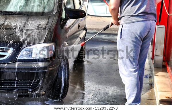 Cleaning Car Using High
Pressure Water. Man washing his car under high pressure water in
service
