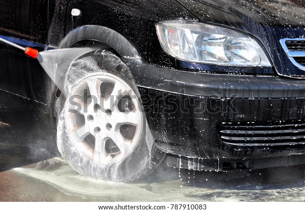 Cleaning Car Using High\
Pressure Water. Man washing his car under high pressure water in\
service