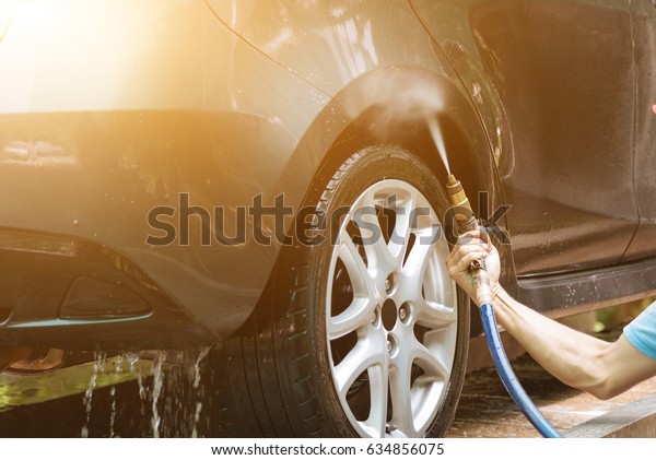 Cleaning car\
using high water pressure, hand hold the high pressure water nozzle\
in selective focus, focus at\
hand.