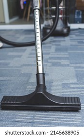 Cleaning The Carpet Flooring Of An Office With A Vacuum Cleaner With An Attached Upholstery Nozzle.