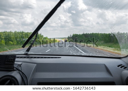 Cleaning the car's windshield with a windscreen wiper. Inside view